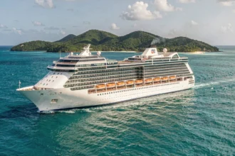 Grand bateau de croisière tout inclus naviguant dans les eaux turquoise des Caraïbes avec une île tropicale en arrière-plan