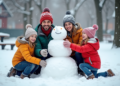 Famille de quatre construisant un bonhomme de neige en hiver
