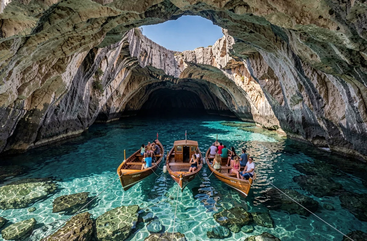Vue panoramique de plusieurs bateaux de touristes à l'intérieur d'une grande grotte marine de Polignano a Mare avec ouverture vers le ciel
